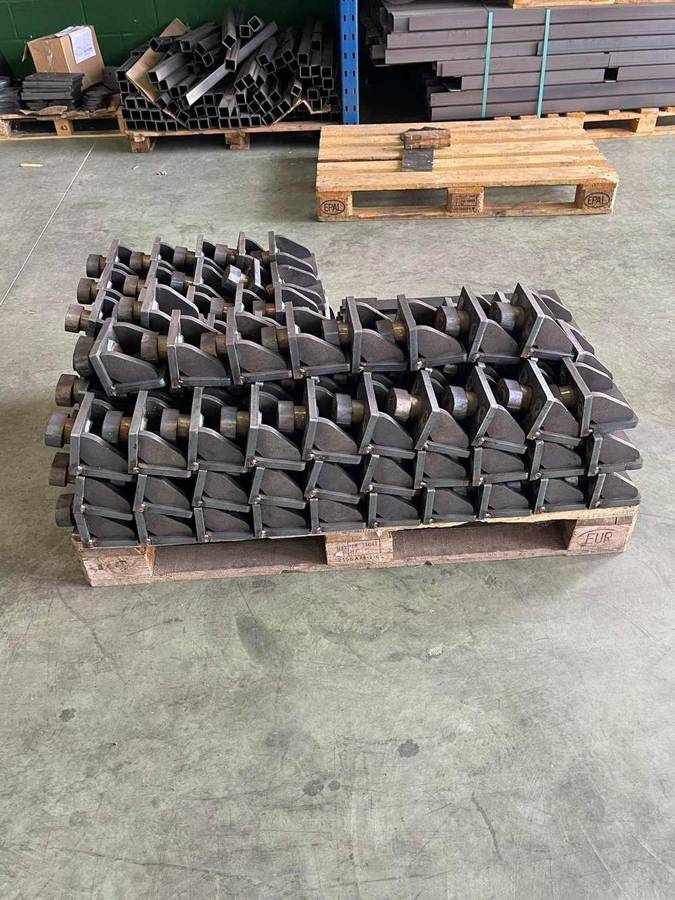 Piezas metálicas apiladas en almacén industrial con racks y estanterías